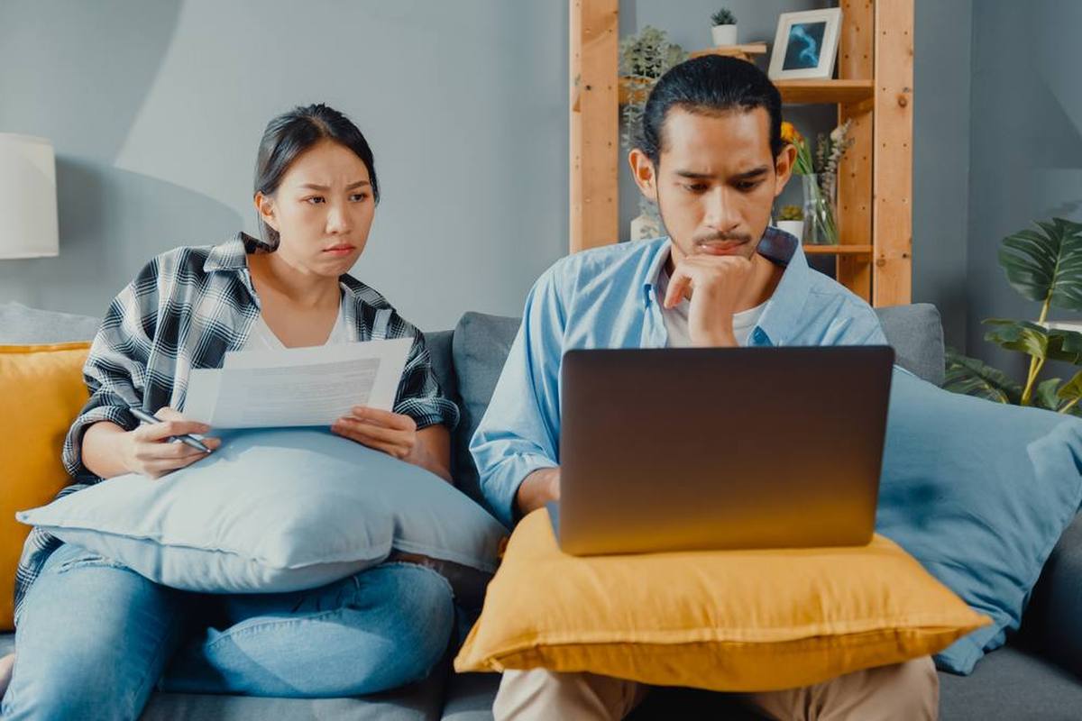 A couple on a sofa going through documents and a laptop at home