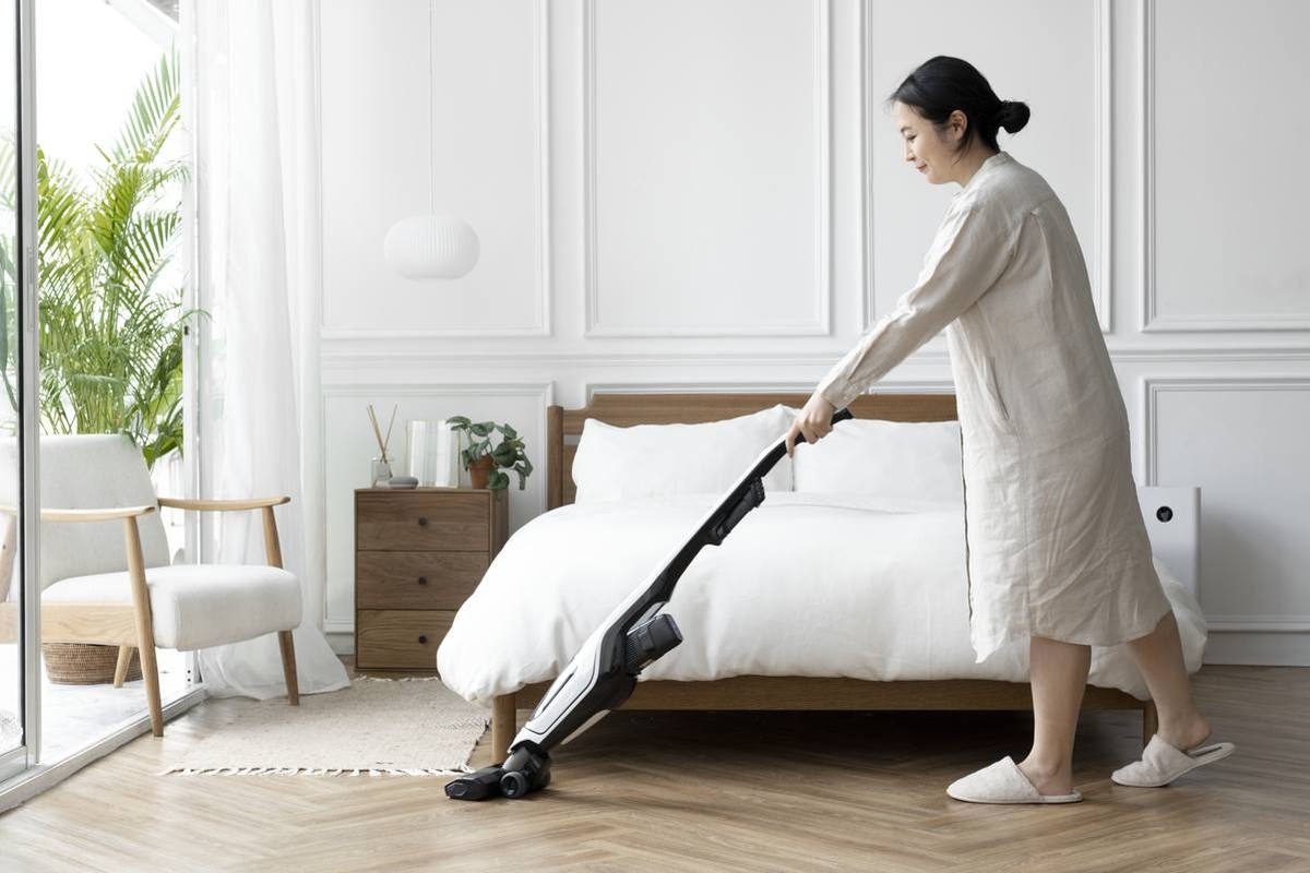 Woman vacuuming a bedroom