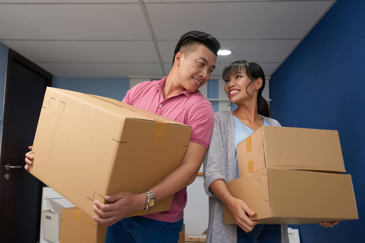 Couple carrying moving boxes into a new home