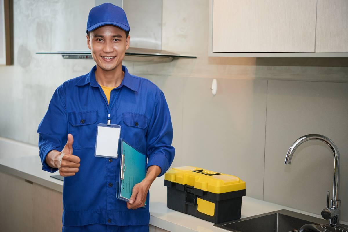 Plumber with a toolbox standing by a kitchen sink