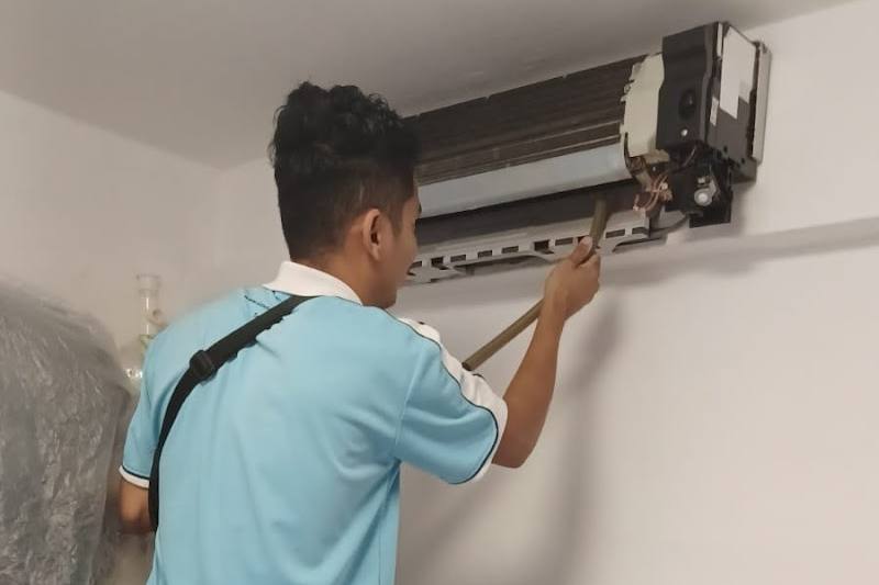 Technician working on a wall-mounted aircon unit by Cool Channels Engineering