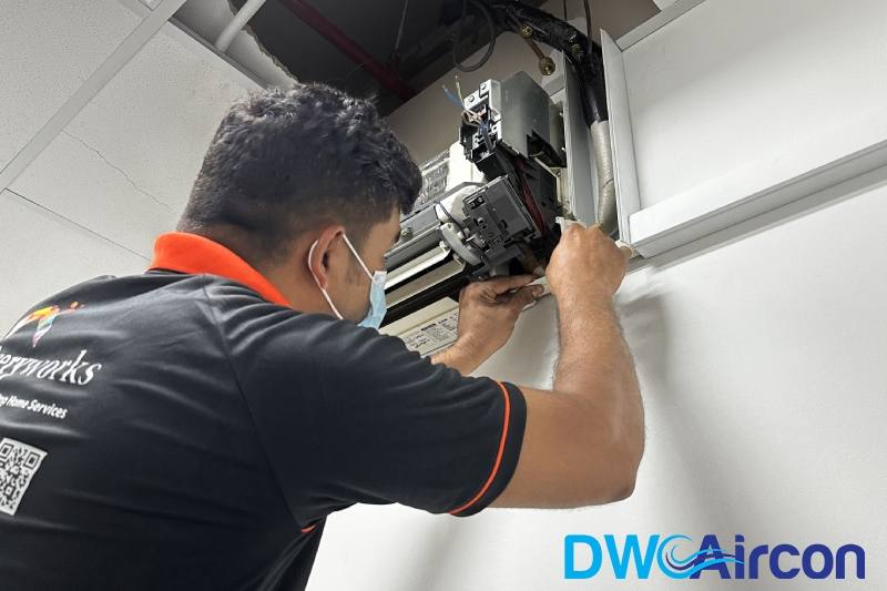 A technician servicing a ceiling cassette aircon by DW Aircon