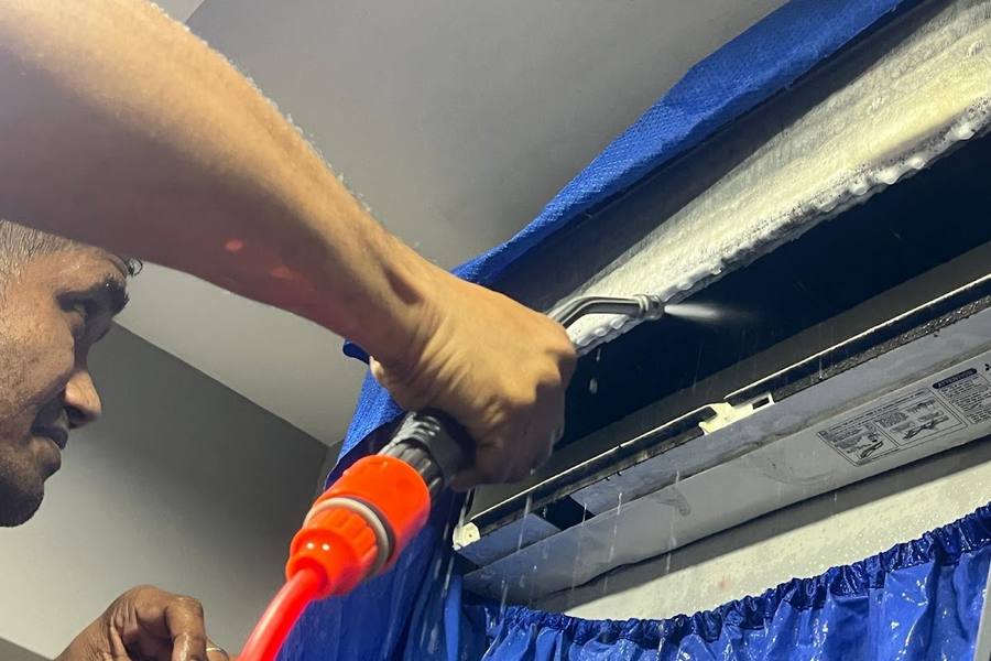 A technician chemical-washing a wall aircon unit by Nimbus Homes