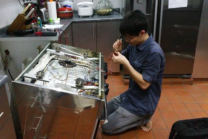 Technician rewiring a gas cooker in a kitchen by HomeUnited Repair