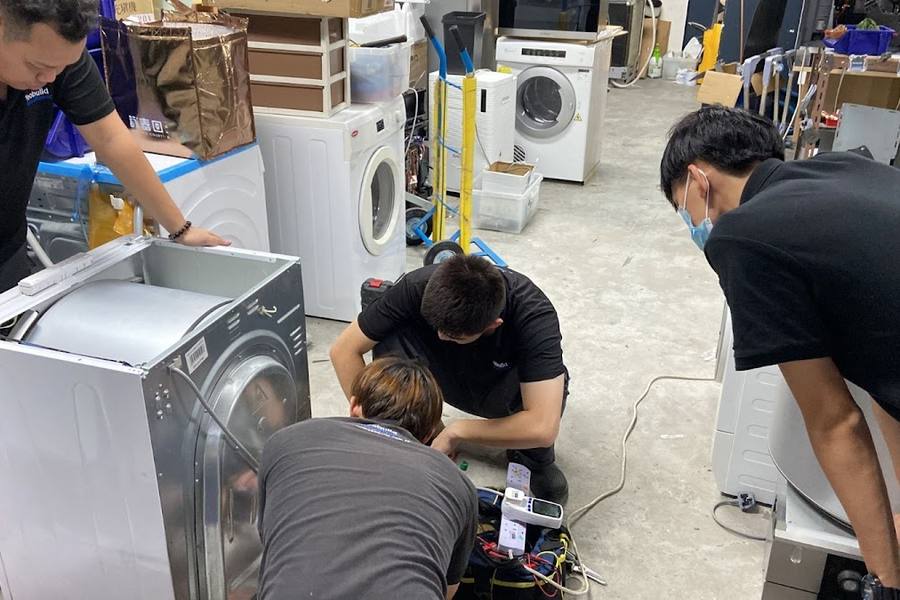 Technicians testing a washer-dryer in a workshop by Yeobuild HomeRepair