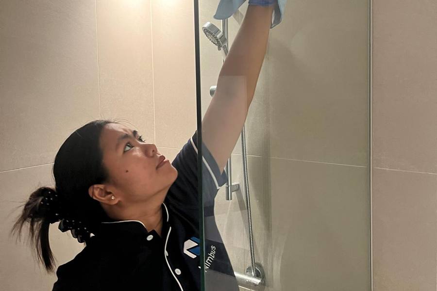 A cleaner wiping a shower screen by Nimbus Homes