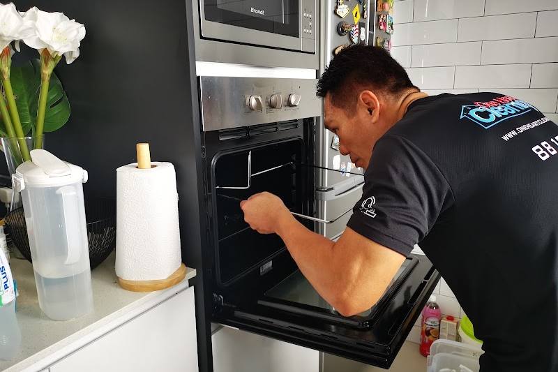 Cleaner cleaning inside an oven by One Heart Cleaning