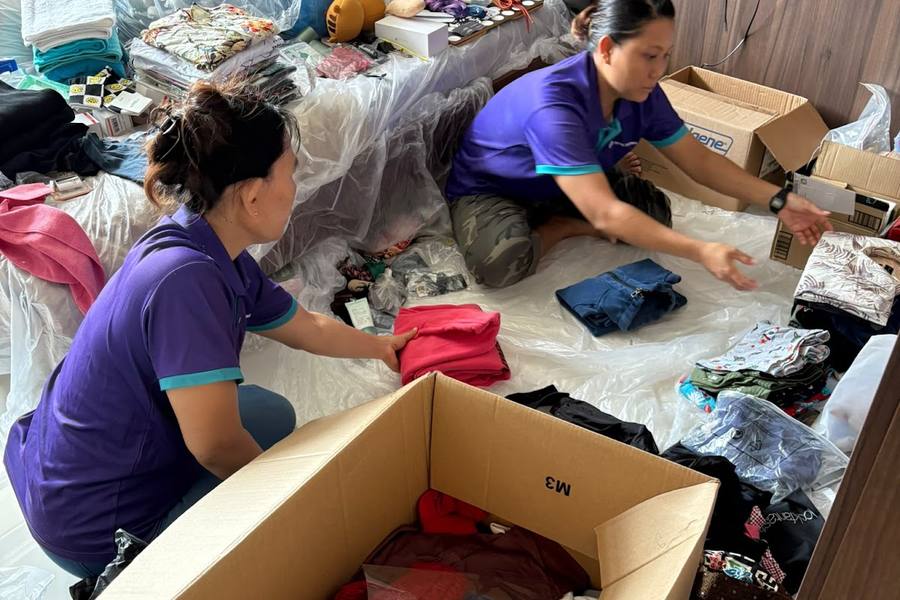 Two staff sorting and packing clothes in a home by Total Cleanz