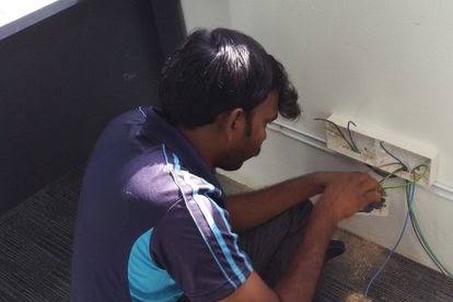 Technician wiring a wall socket by Everyworks