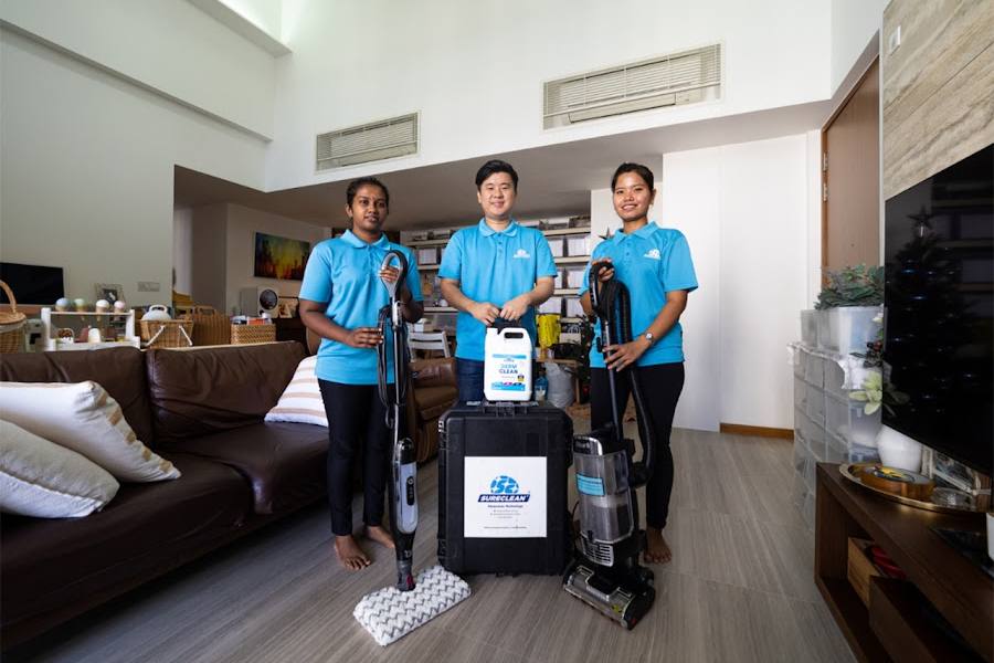 Three cleaners with vacuum and cleaning equipment in a living room by Sureclean