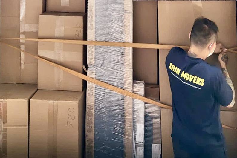 A mover strapping boxes inside a truck by Shin Movers & Logistics