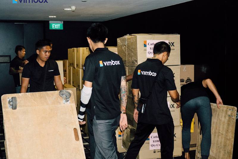 Movers carrying boxes on trolleys by Vimbox Movers