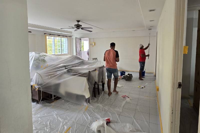 Painters at work in a flat with the floor and furniture covered by Affordable Painting SG