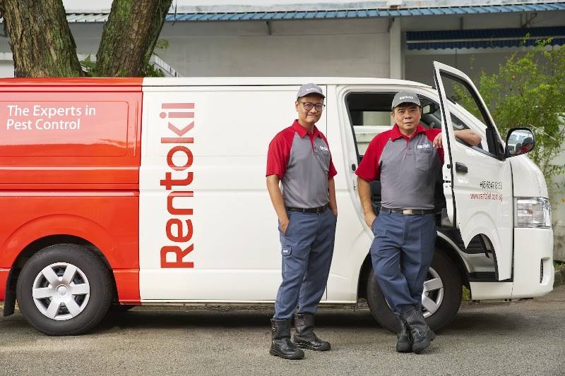 Two technicians standing beside a company van by Rentokil