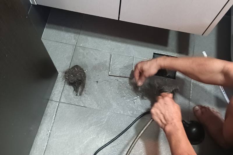 Plumber clearing a choked floor trap by HW Singapore Licensed Plumber