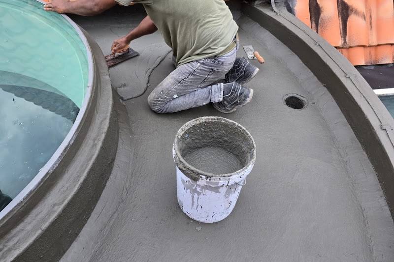 Worker waterproofing a flat roof by K. Heng Plumbing