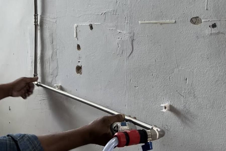 Plumber fitting a new water pipe along a wall by PW Plumbing Services