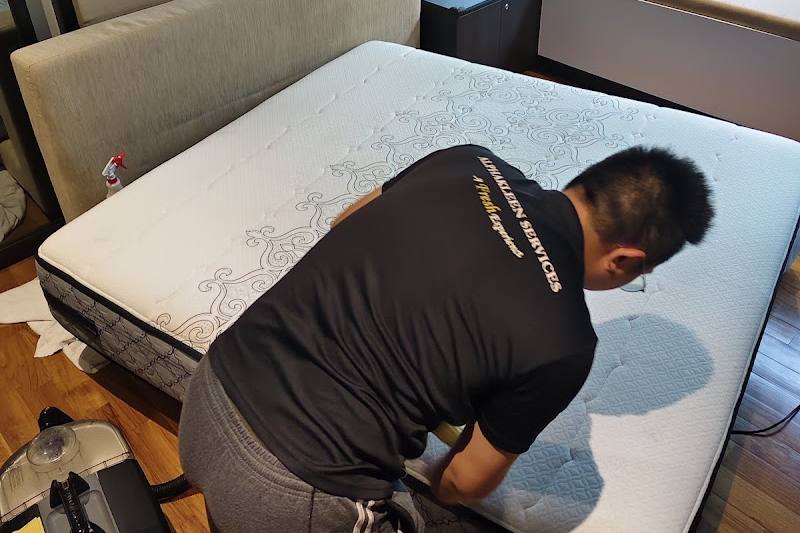 Technician in an AlphaKleen shirt cleaning a mattress by AlphaKleen Services