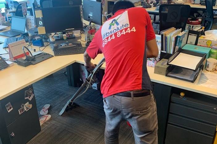 Technician cleaning office carpet between desks by Singapore Carpet Cleaning