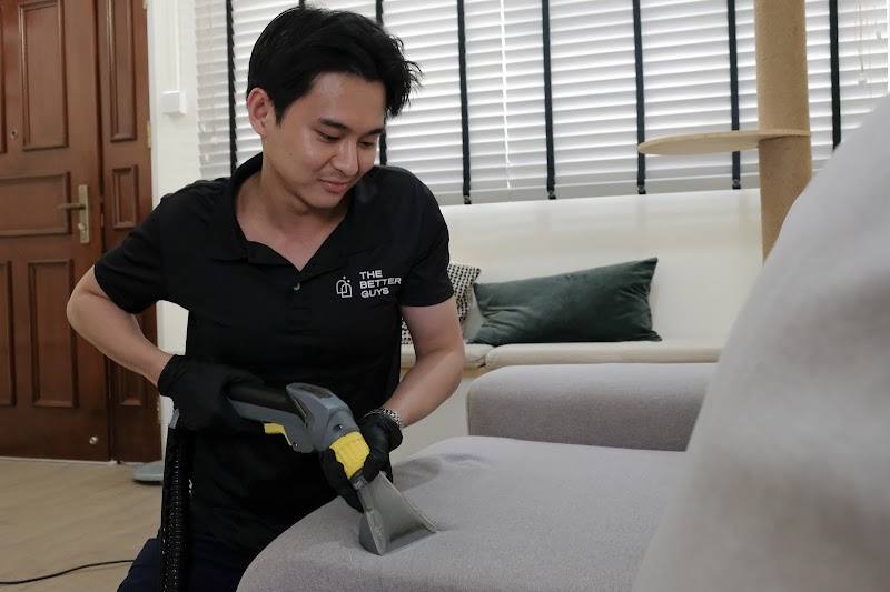 Staff member steam-cleaning a fabric sofa by The Better Guys